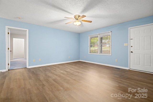 spare room featuring visible vents, baseboards, a ceiling fan, and wood finished floors