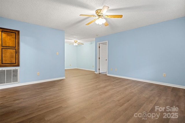 empty room featuring baseboards, a ceiling fan, visible vents, and dark wood-style floors