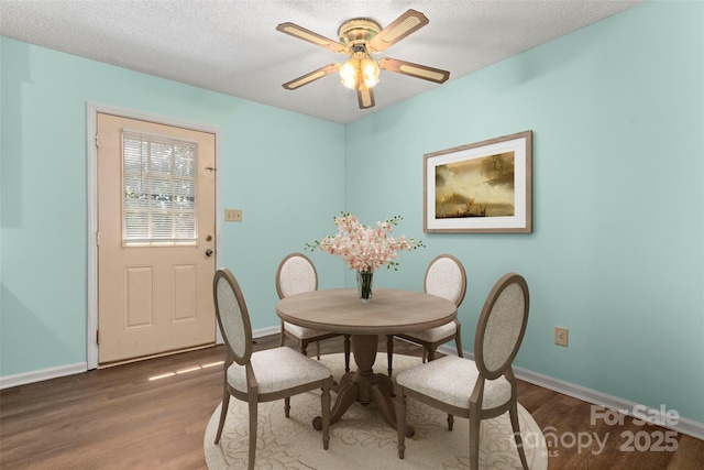dining space featuring baseboards, a ceiling fan, wood finished floors, and a textured ceiling