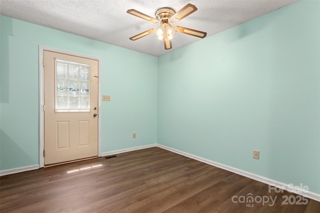 interior space with dark wood finished floors, baseboards, visible vents, and ceiling fan