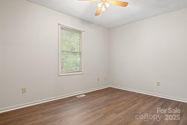 spare room with dark wood-style floors, visible vents, a ceiling fan, baseboards, and a textured ceiling