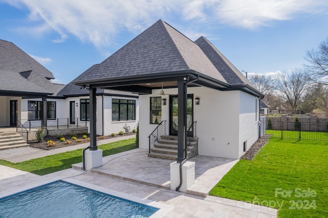 rear view of house featuring a patio area, a fenced in pool, and a lawn