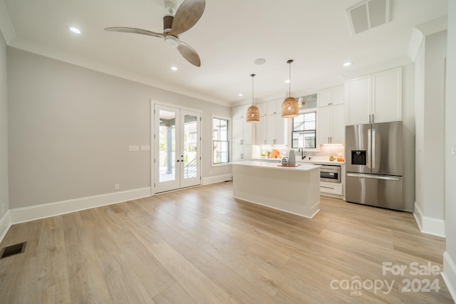 kitchen with stainless steel fridge, decorative light fixtures, french doors, a kitchen island, and white cabinets