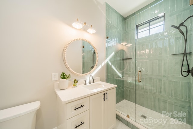 bathroom featuring a shower with shower door, toilet, and vanity