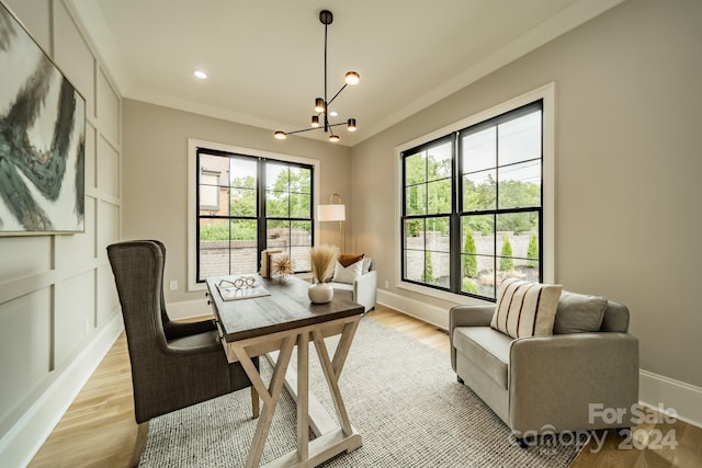 office area with a healthy amount of sunlight, light wood-type flooring, a notable chandelier, and ornamental molding