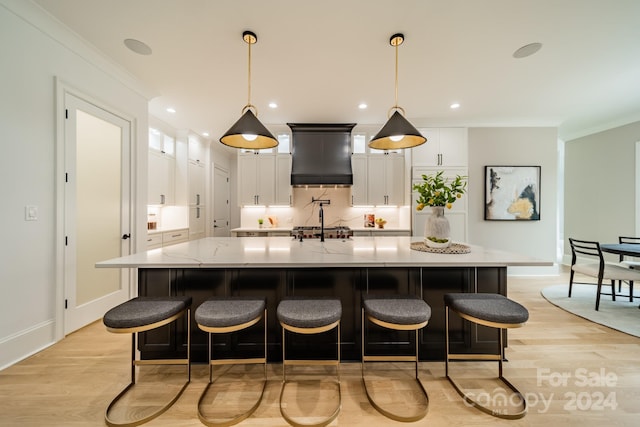 kitchen with premium range hood, white cabinetry, a spacious island, ornamental molding, and pendant lighting