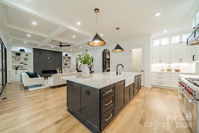 kitchen featuring decorative light fixtures, beam ceiling, double oven range, sink, and white cabinetry