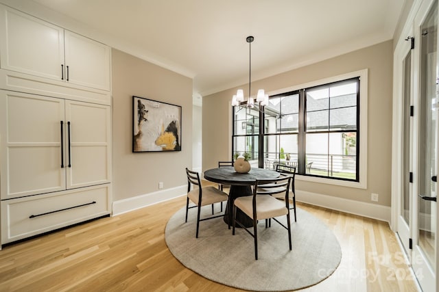 dining space with light wood-type flooring, a notable chandelier, and ornamental molding