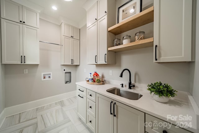 kitchen featuring light stone countertops, ornamental molding, white cabinets, and sink