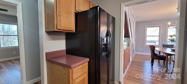 kitchen featuring black fridge with ice dispenser and light hardwood / wood-style flooring