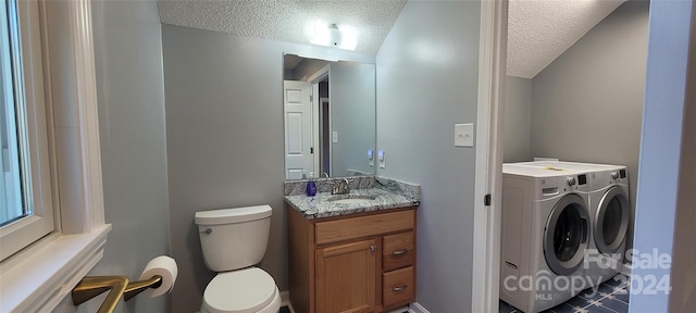 bathroom with a textured ceiling, toilet, vanity with extensive cabinet space, and washing machine and clothes dryer