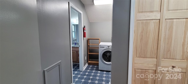 washroom with a textured ceiling, dark tile flooring, and washer / dryer