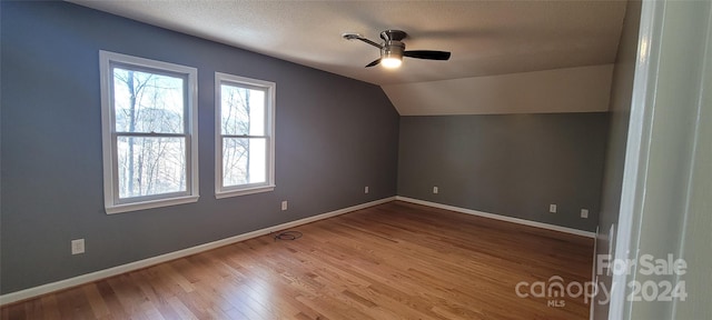 additional living space featuring a textured ceiling, wood-type flooring, ceiling fan, and vaulted ceiling