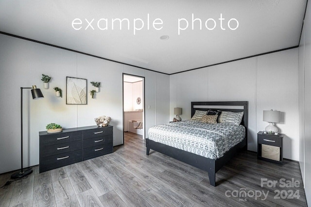 bedroom with ensuite bath and wood-type flooring