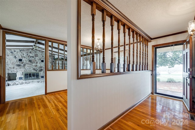 interior space featuring vaulted ceiling, a textured ceiling, light hardwood / wood-style floors, ceiling fan with notable chandelier, and a stone fireplace