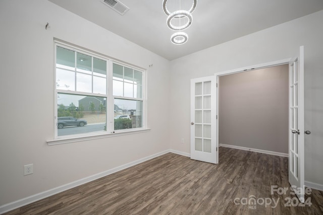 unfurnished room featuring a chandelier, french doors, and dark wood-type flooring