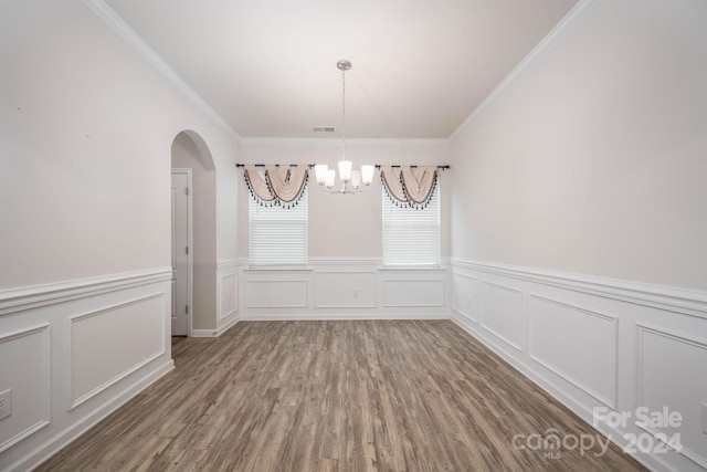 unfurnished dining area with hardwood / wood-style floors, a notable chandelier, and crown molding