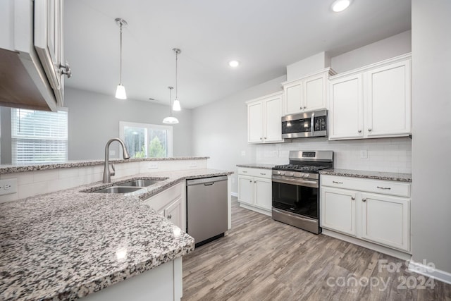 kitchen featuring pendant lighting, sink, light hardwood / wood-style flooring, stainless steel appliances, and white cabinetry