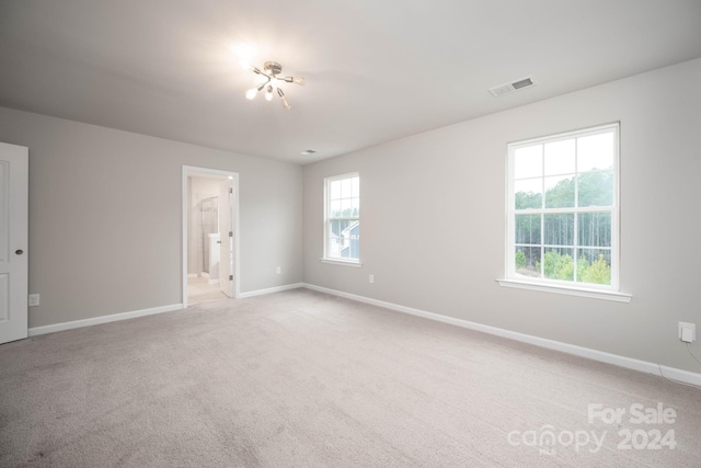 empty room featuring an inviting chandelier and light colored carpet