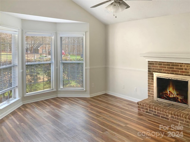 unfurnished living room featuring lofted ceiling, ceiling fan, a brick fireplace, and dark wood-type flooring