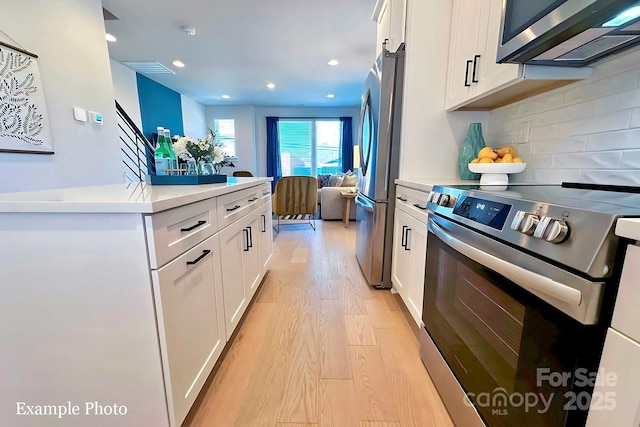 kitchen featuring decorative backsplash, white cabinets, light hardwood / wood-style flooring, and stainless steel appliances