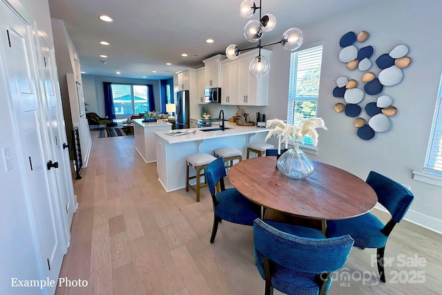 dining space with sink and light wood-type flooring