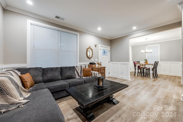 living room with an inviting chandelier, ornamental molding, and light hardwood / wood-style floors