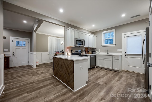 kitchen featuring dark wood-type flooring, stainless steel appliances, sink, white cabinetry, and crown molding