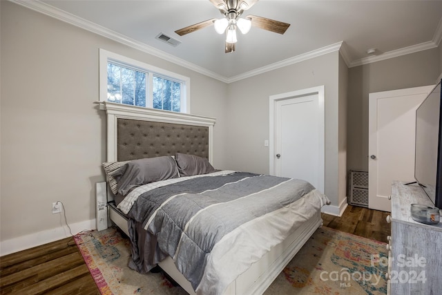 bedroom featuring dark hardwood / wood-style floors, ornamental molding, and ceiling fan