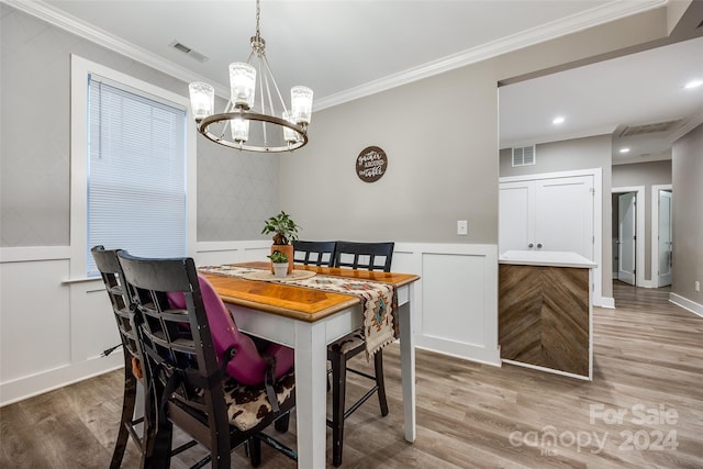 dining space with a notable chandelier, ornamental molding, and hardwood / wood-style floors