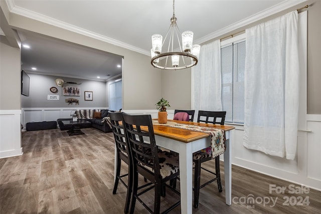 dining area featuring ornamental molding, hardwood / wood-style floors, and a notable chandelier