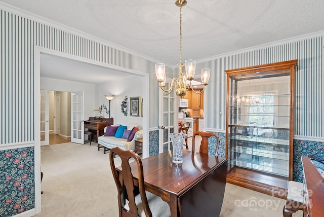 carpeted dining space featuring ornamental molding, a textured ceiling, french doors, and a notable chandelier