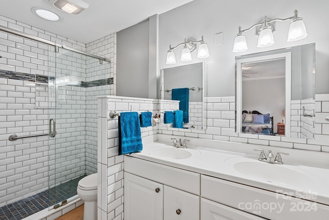 bathroom featuring oversized vanity, a shower with shower door, toilet, tasteful backsplash, and dual sinks