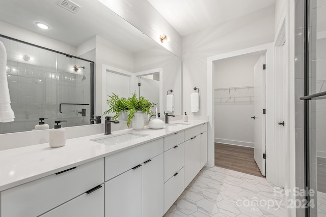 bathroom featuring large vanity, tile floors, double sink, and walk in shower