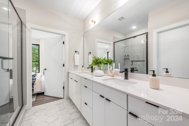 bathroom featuring dual bowl vanity, tile floors, and walk in shower