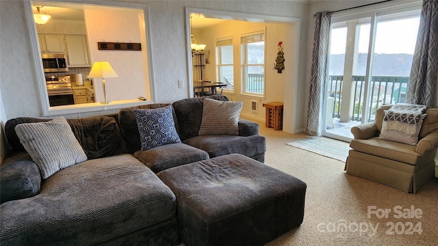 living room featuring plenty of natural light, light carpet, and a chandelier