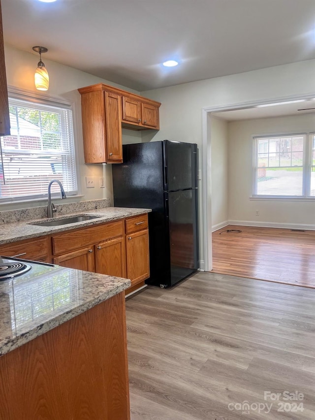 kitchen featuring sink, plenty of natural light, black refrigerator, and light hardwood / wood-style floors