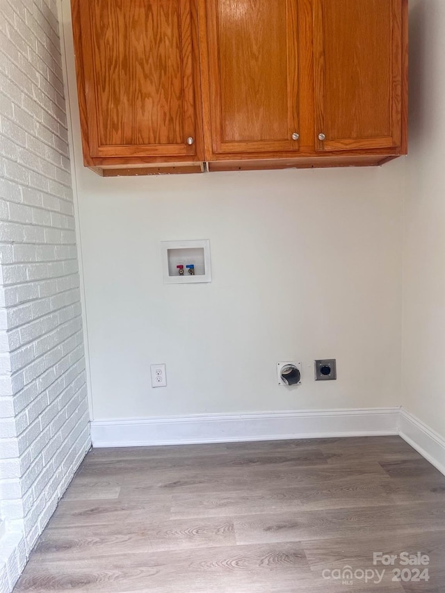 laundry room with brick wall, washer hookup, light hardwood / wood-style flooring, and cabinets