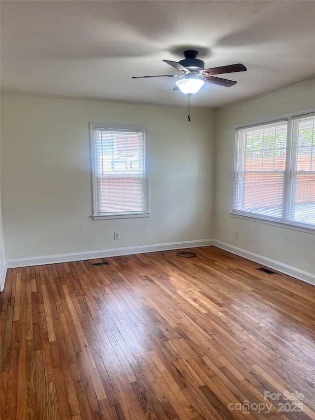 empty room featuring hardwood / wood-style flooring, a wealth of natural light, and ceiling fan