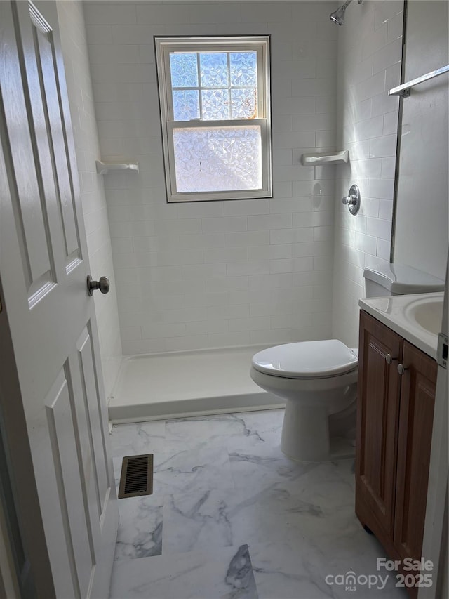 bathroom featuring tiled shower, vanity, and toilet