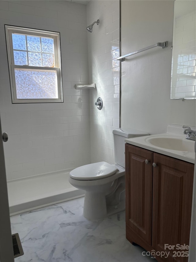 bathroom featuring vanity, toilet, and tiled shower