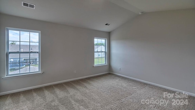 carpeted spare room featuring vaulted ceiling