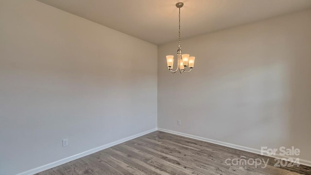 unfurnished room featuring an inviting chandelier and dark wood-type flooring