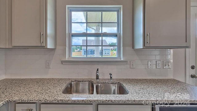 kitchen featuring a wealth of natural light, tasteful backsplash, and sink