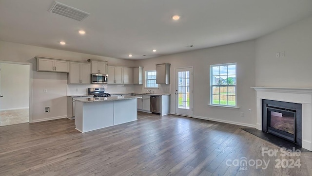 kitchen with gray cabinetry, a kitchen island, appliances with stainless steel finishes, and dark wood-type flooring