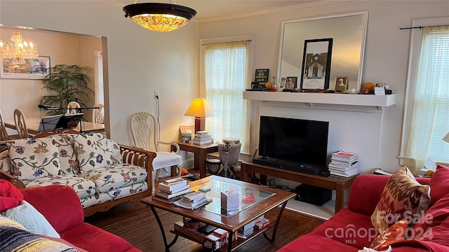 living room featuring wood-type flooring, crown molding, and a notable chandelier