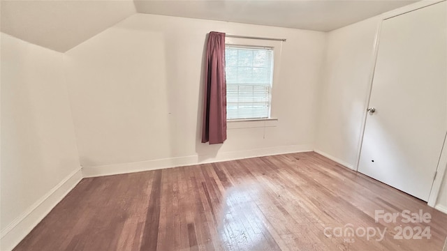 empty room with vaulted ceiling and light hardwood / wood-style flooring