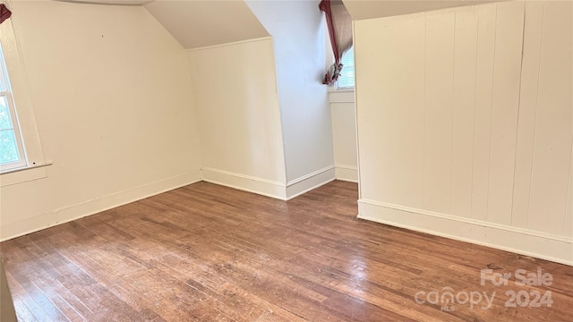 unfurnished room featuring wood-type flooring, vaulted ceiling, and wood walls