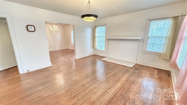 interior space featuring a healthy amount of sunlight, crown molding, an inviting chandelier, and wood-type flooring