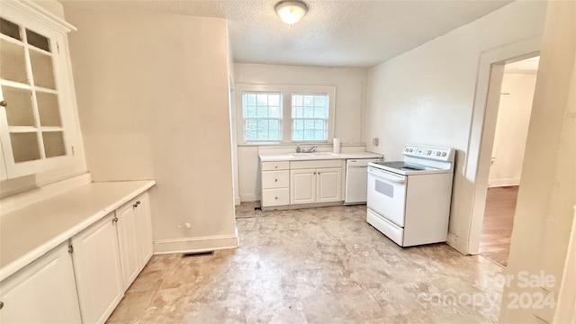 kitchen featuring a textured ceiling, sink, white appliances, and white cabinetry